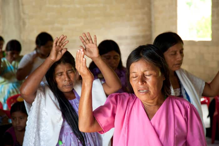Women raise their hands in the air and pray during a time of worship in the local church.